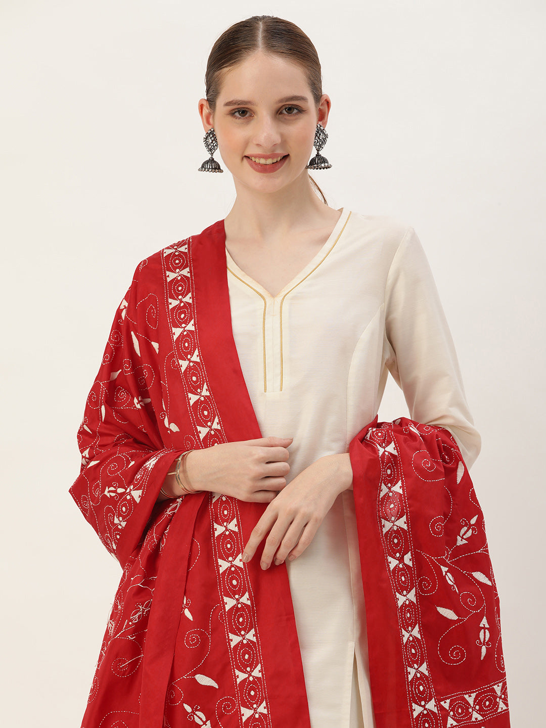 A woman wearing a red and white floral kantha silk dupatta with intricate handwork, paired with a white top.
